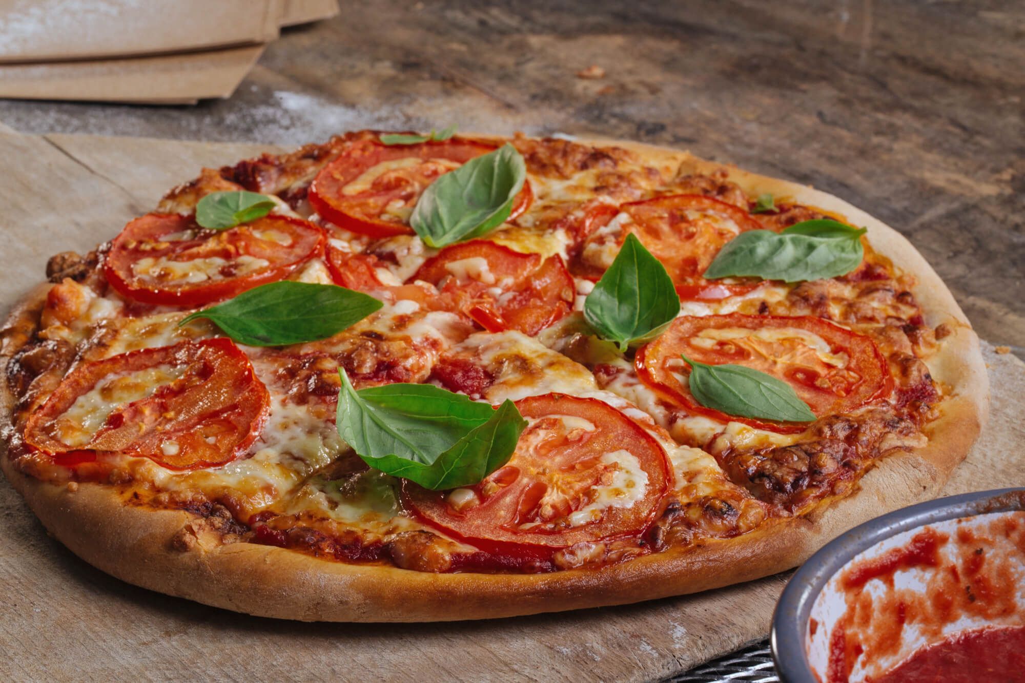 A delicious pizza topped with fresh tomatoes and basil on a rustic wooden cutting board.