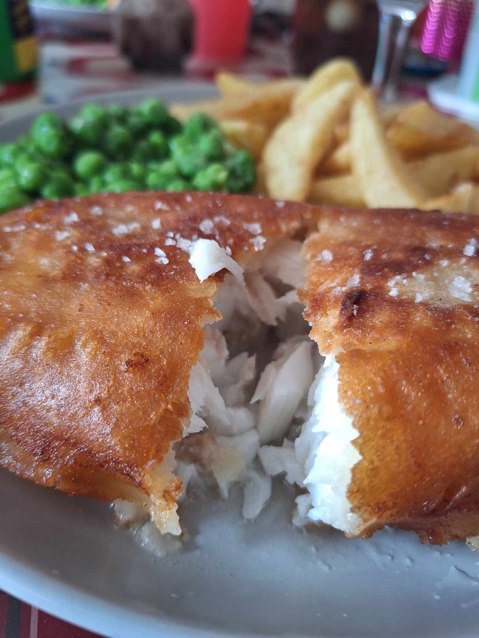 A white plate with golden fried fish and french fries.  The fish has a crispy beer batter.