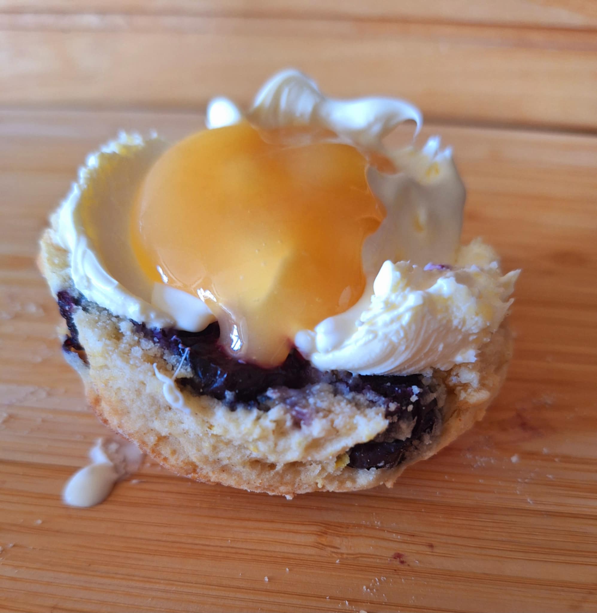 Split scone topped with clotted cream and lemon curd alongside a cup of tea
