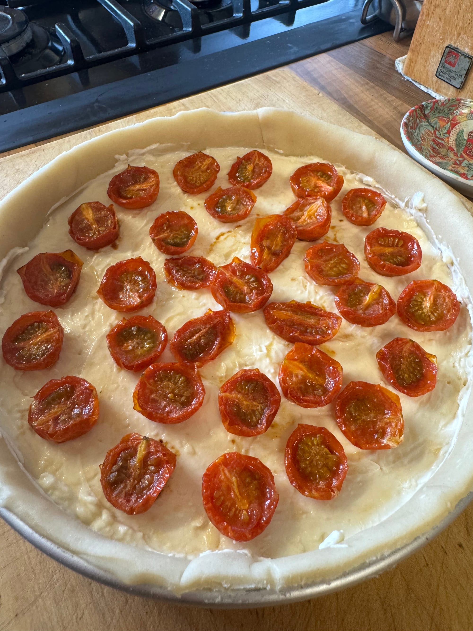 Arranging roasted cherry tomatoes evenly over cheese custard in tart case