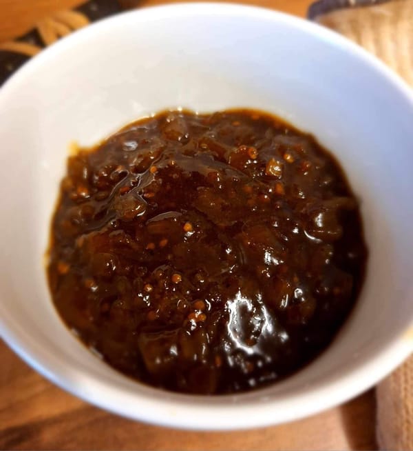 A bowl of brown Autumn Curried Green Tomato Chutney displayed on a table, ready to enhance any meal.
