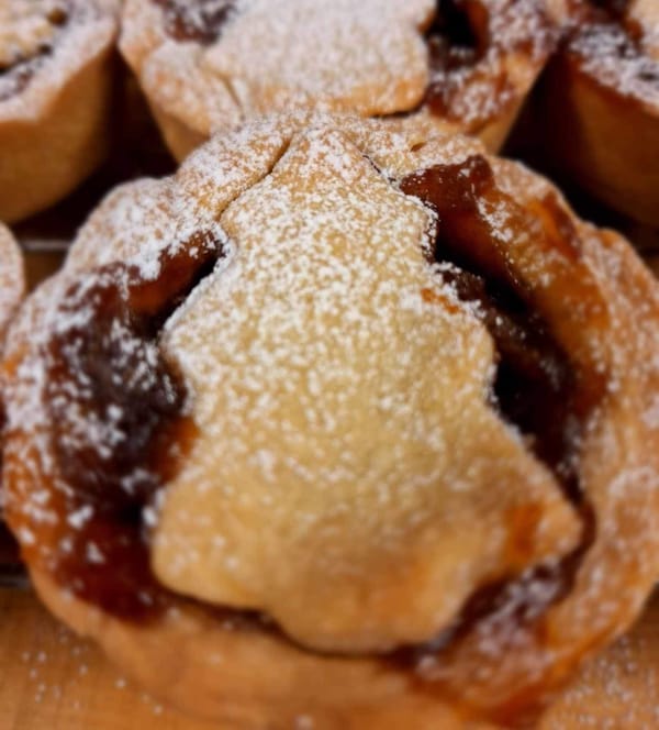 Close-up of a golden-brown mince pie topped with powdered sugar.