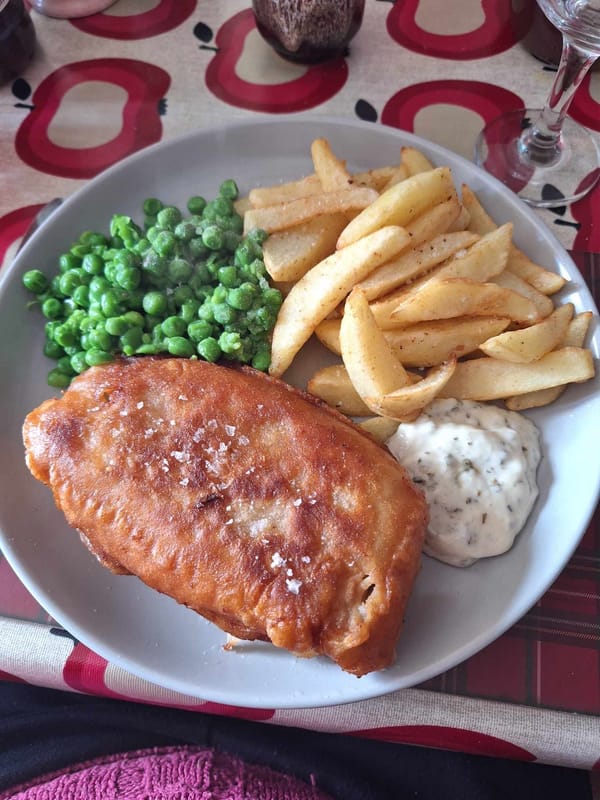 Crispy beer battered fish and golden chips on white plate
