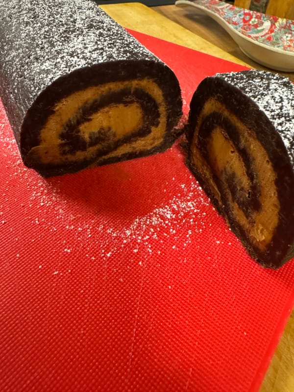 A homemade chocolate yule log with a Biscoff filling, dusted with powdered sugar.