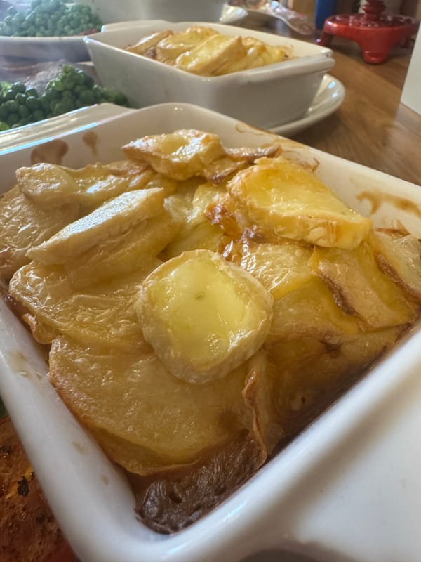 A golden-brown, cheesy potato gratin with melted cheese on top, served in a white baking dish