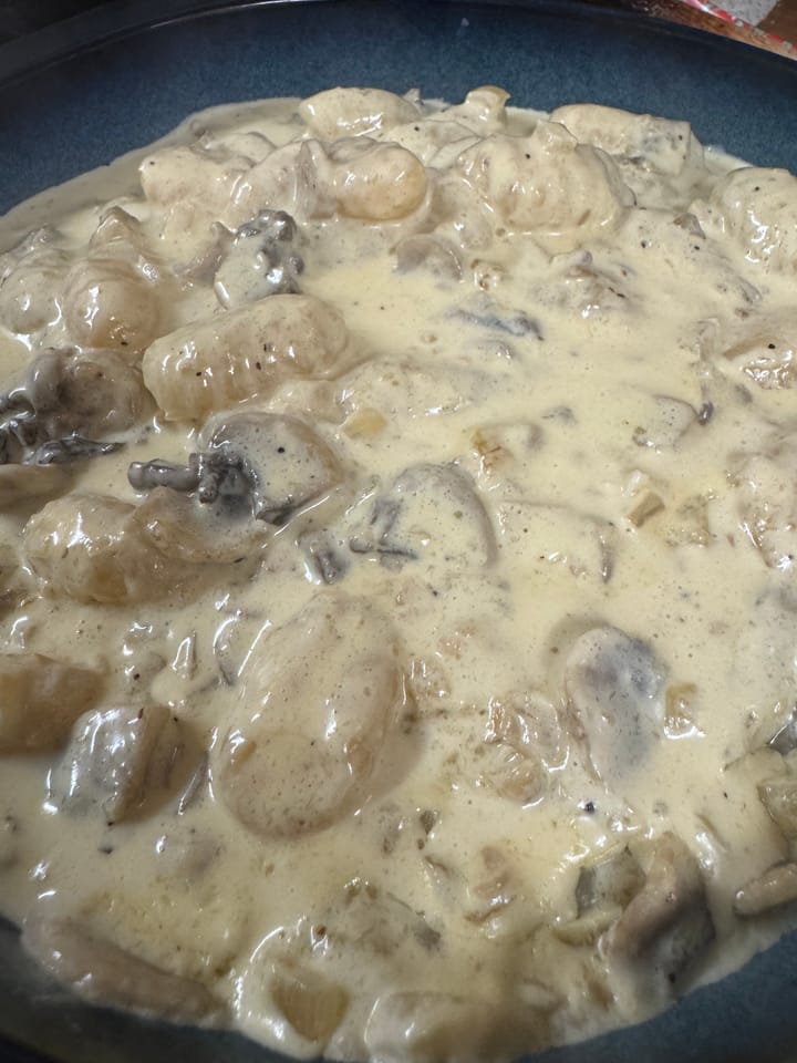 A bowl of creamy garlic and mushroom gnocchi with a delicious sauce on top.